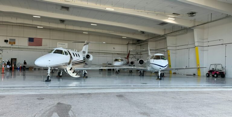 three private jets in an airport hanger, one jet preparing to board passengers